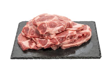 Yığılmış domuz bifteği tabakta. Bir yığın taze domuz bifteği siyah bir tabakta duruyor. Parçalar güçlü bir bilye gösteriyor ve ızgara ya da tavaya hazırlar..