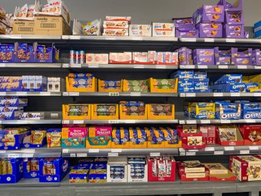 Almanya 7 Haziran 2025. Çeşitli kurabiyeler, bisküviler ve tatlı atıştırmalıklarla dolu bir raf. Oreo, Milka ve Nutella gibi popüler markalar belirgin bir şekilde sergilenmektedir..