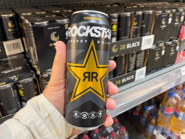 Almanya 7 Haziran 2025. Bir el, süpermarkette bir kutu Rockstar Enerji İçeceği tutuyor. Arka planda daha fazla enerji içeceği var..