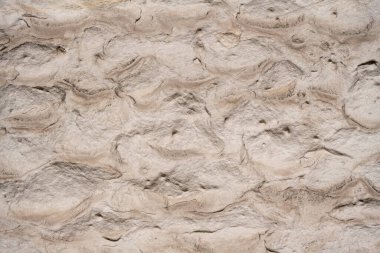 Kabataslak, dalgalı taş bir duvarın yakın görüntüsü. Doğal bej renkler ve oyulmuş desenler eşsiz bir mimari arkaplan sağlar.