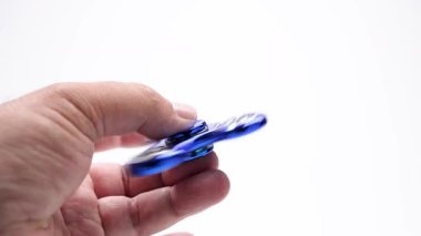 Dönen mavi fırıldak iki parmağın arasında yatay olarak tutulur. Kamera düz beyaz bir arkaplan üzerinde düz hareket ve döndürme kaydeder.