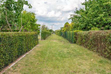 Çitli Bahçe Yolu. Bahçe bahçesindeki sık çitler arasında iyi korunmuş bir çayır yolu var. Sokak tabelaları ve sokak lambaları düzenli bir bahçe alanı olduğunu gösteriyor..