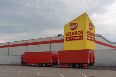 Almanya 14 Temmuz 2025. Kamyonu olan Selgros. Selgros Cash and Carry 'nin sarı girişinin önüne kırmızı bir tır park etmiş. Kırmızı çizgili toptan bina sahneye hakim..