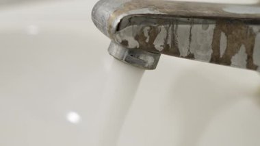 Musluktan dökülen suyun yakın çekimi. Musluk suyunun görünür damlacıklarıyla yakın plan görüntüsü. Saflık ve temizliğe vurgu.