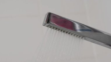 Duş Başlığı Su Akışı. Suyun aktığı modern bir duş başlığının yakın çekimi. Nazik sprey ve temiz beyaz arkaplan.