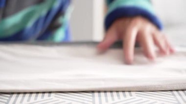 Beyaz bir kumaşa baskı yapan ütünün yakın çekimi. Yumuşak desenli ütü tahtası giysiyi destekler.