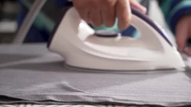 Buharlı ütünün yakın plan gri kumaşı. Kalıplı kumaş desenli tahtaya karşı düz duruyor..