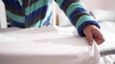 Buhar ütüsü beyaz gömleğin üzerinde süzülürken diğer el kumaşı gerer. Kırışıklıklar anında kaybolur..