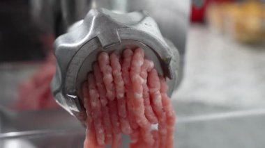 Kıyma makinesinden çıkan uzun kıyma telleri. Makine sürekli çalışıyor..