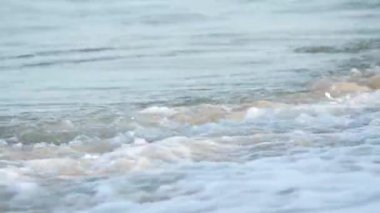 Beyaz köpükle hafifçe kırılan dalganın yakın çekimi. Su sorunsuz ve sakince akıyor..