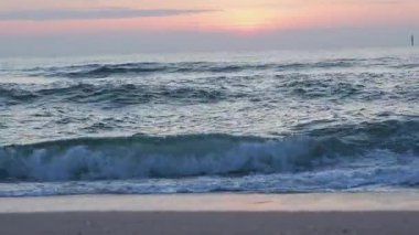 Gün batımının ışığında dalgaların yaklaşması. Suyun yüzeyi yavaşça parıldıyor..