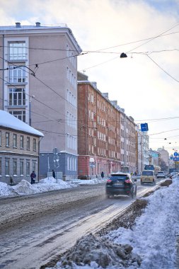 Riga, Letonya - 8 Aralık 2022: Karlı kış caddesinde modern tramvay ve arabalar. Dikey çekim.