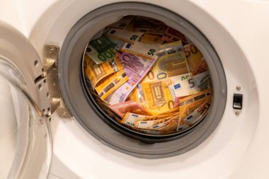 Closeup of a big pile of money in an open washing machine. Money laundering concept. clipart