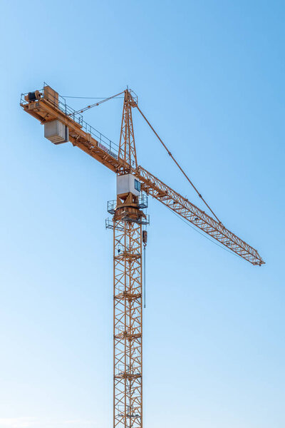 Tower construction crane against blue sky. Vertical shot.