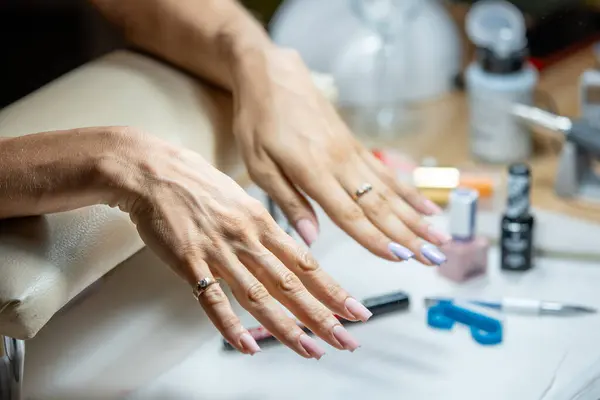 Close-up shot of a woman hand in a nail salon receiving manicure. Woman getting nail manicure at spa centre.