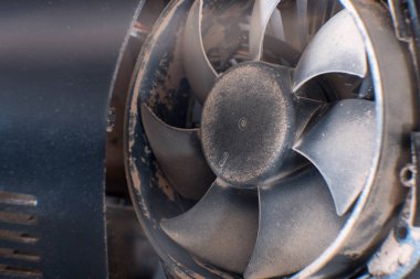 Temiz beyaz bir masa üstünde dinlenen kirli metal bir bilgisayar vantilatörünün detaylı bir görüntüsü. Alaşımlı tekerlekler, jantlar ve jant kapakları gibi otomotiv lastiği bileşenlerini hatırlatıyor.