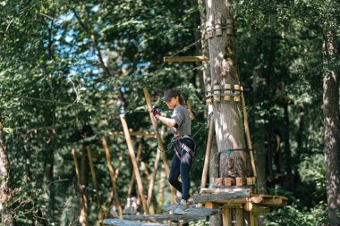 Canlı yeşillik ve heyecan içinde zorlu bir ağaca tırmanma kursunda ustaca yol alan bir birey.
