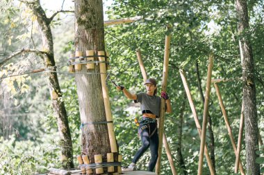 Maceraperest bir dağcı ustalıkla yol yordam bilen ipler ve ahşap yapılar ve canlı bir açık hava ortamı.