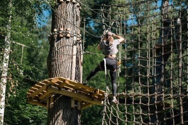Ağaçların arasında yer alan ve hem heyecan hem de macera içeren ipleri ustaca kullanan bir kişi.