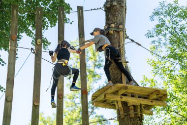 İki kız, zorlu bir yüksek ip kursunda ustalıkla yol alarak takım çalışmalarını ve macera ruhlarını sergilediler.