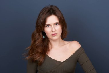 Kestane rengi saçlarıyla doğrudan kameraya bakan genç ve güzel bir kadın.