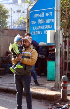 DELHI INDIA - 02 12 2023: Yeni Delhi parkında oğluyla poz veren Hintli genç adam portresi