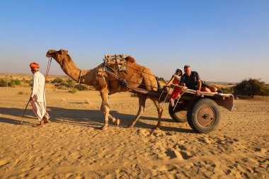THAR RAJASTHAN INDIA - 02 13 2023: Thar çölünün kum tepelerinde develeri olan Hint deve sürücüsü. Jaisalmer, Rajasthan, Hindistan