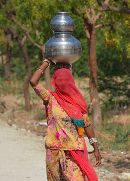 stock image RURAL RAJASTHAN INDIA - 02 13 2023: Tribal life village life women carrying water in pots on head summer water shortage