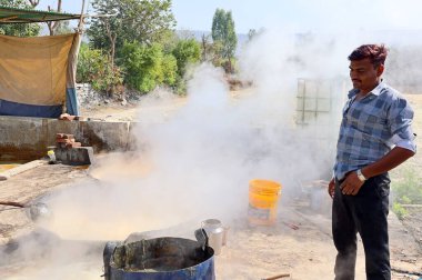RURAL RAJASTHAN Hindistan - 02 16 2023: Kaynar şeker kamışı fabrikasında çalışan adam