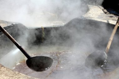 RURAL RAJASTHAN Hindistan - 02 16 2023: Kaynar şeker kamışı fabrikasında çalışan adam