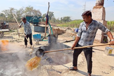 RURAL RAJASTHAN Hindistan - 02 16 2023: Kaynar şeker kamışı fabrikasında çalışan adamlar