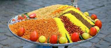 Meyve pazarında bir tabak baharat, fıstık ve sebze.