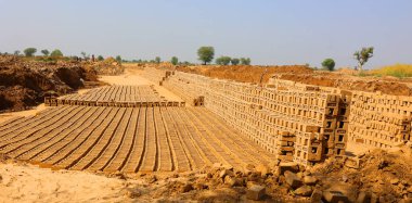 UTTAR PRADESH INDIA - 03 01 2023: Ham tuğla kurutmak için istiflenmiş. Tuğla fabrikasında tuğlalar. Hindistan 'da geleneksel kil tuğla üretimi.