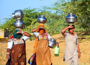 DESERT JAISALMER RAJASTHAN Hindistan - 02 13 2023: Rajasthani kadınları kafalarında su kavanozları taşıyorlar. Ülke dünya nüfusunun yüzde 18 'ine sahip olmasına karşın, su kaynaklarının sadece yüzde 4' ü 
