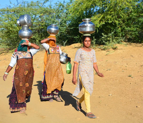 stock image THAR DESERT JAISALMER RAJASTHAN INDIA - 02 13 2023: Rajasthani women carrying water jars in the head. The country has 18 percent of the world's population, but only 4 percent of its water resources  