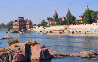 ORCCHA INDIA - 03 03 2023: Orchha 'nın Bundela Rajput krallarının kralları Betwa nehrinin kıyısında tarihin sessiz nöbetçileri gibi duruyorlar. Ghat 'ın merdivenlerinde ayin banyosu