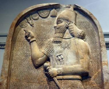 LONDRA BİRLİK KINGDOM 06 17 2023: Ashurnasirpal II kireçtaşı stela: oyulmuş; kral kraliyet şapkasını konik bir üst ile giyer ve otoriteyi sembolize eden bir gürz tutar