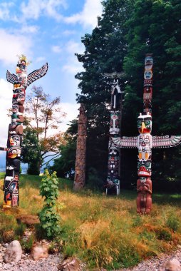 VANCOUVER BC CANADA JUNE 09 2003: The Totem Poles at Brockton Point in Stanley Park are one of the most visited tourist attractions. Carvings symbolize tales familiar to Native Americans clipart