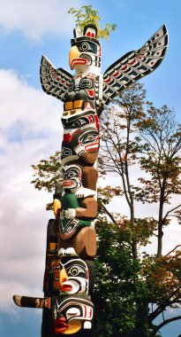 VANCOUVER BC CANADA JUNE 09 2003: The Totem Poles at Brockton Point in Stanley Park are one of the most visited tourist attractions. Carvings symbolize tales familiar to Native Americans clipart