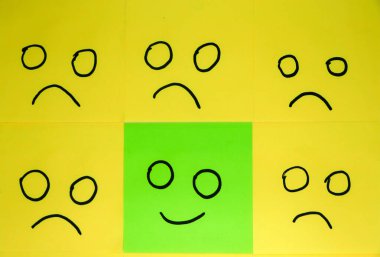 Emotions concept. Background of sticky notes. Green sticky note is among yellow sticky notes.