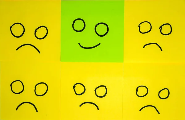 Emotions concept. Background of sticky notes. Green sticky note is among yellow sticky notes.