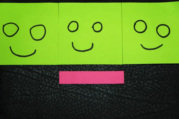 Unhappy and happy concept. Background of green sticky notes. Unhappy sticky note is among happy sticky notes.