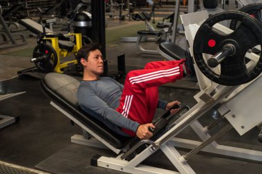 Modern bir spor salonunda dambılla spor yapan eşcinsel bir adam..