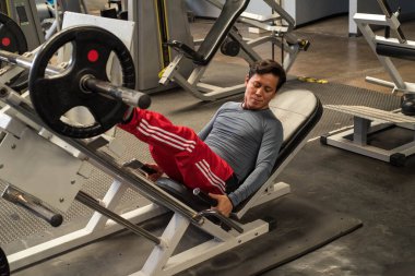 Modern bir spor salonunda dambılla spor yapan eşcinsel bir adam..