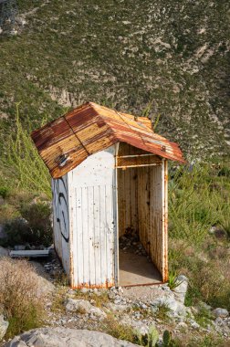 Paslı bir çatısı ve doğal bir dağ manzarası olan kırsal ve yıpranmış bir bina keşfedin.