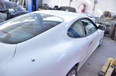 TORREON, COAHUILA, MEXICO; 30 Temmuz 2025 Parlak, iyi donanımlı bir oto tamirhanesinde yenilenen klasik beyaz spor araba