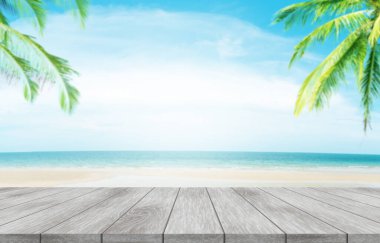 Yaz tatili konsepti. Beyaz kumlu plajlarda hindistan cevizi palmiyeli ahşap masa, mavi gökyüzü, kristal berrak sular arka plan.