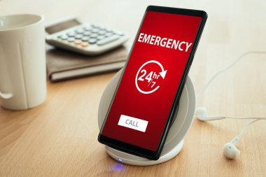 Acil çağrı konsepti. Mobil akıllı telefon bir kablosuz hızlı şarj cihazına yerleştirilir.
