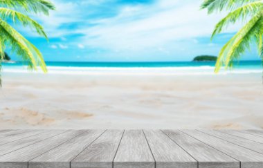 Yaz tatili konsepti. Beyaz kumlu plajlarda hindistan cevizi palmiyeli ahşap masa, mavi gökyüzü, kristal berrak sular arka plan.