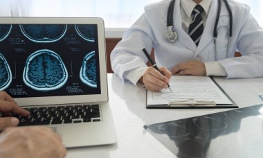 Doktor çalışıyor ve doktor muayenehanesinde çalışan ekiple birlikte tıbbi belgeleri not alıyor..